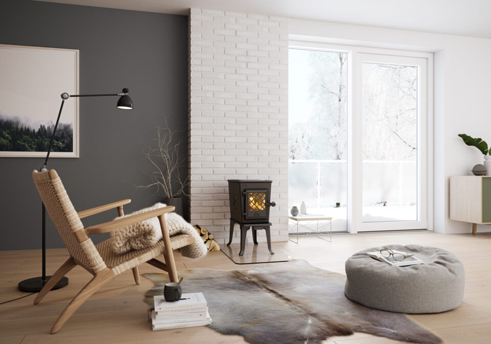 Minimalist living room with a snowy view, wood-burning stove, woven chair, and cozy decor.